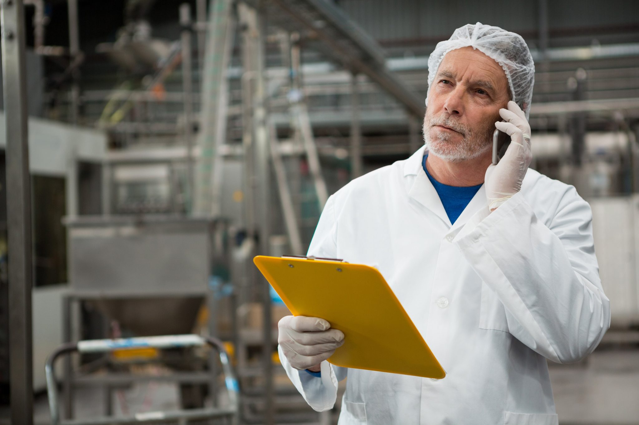 serious male worker talking on mobile phone in cold drink factory